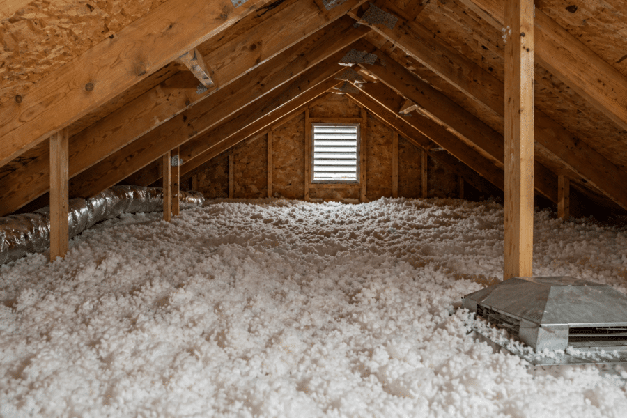 Attic interior showing insulation coverage and roof ventilation components during a home inspection